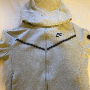 Grå Nike Tech - Säljer min Nike Tech i storlek 147-158 och är i väldigt fint skick
