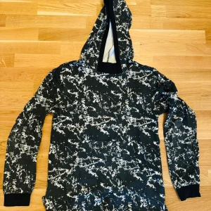 Svart hoodie - Svart hoodie med vita ”blixtrar”. Bra skick använd fåtal gånger. Köpt för 350 säljer för 250 kr. För mer information och bilder kontakta mig. 