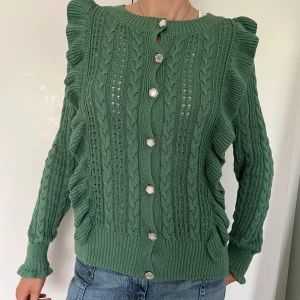 Stickad kofta - Tröjan är utsmyckad med vackra knappar med pärlemor-imitation. På några av knapparna har detta lossnat men inget man tänker på och om man vill kan man lätt flytta knapparna så de med pärlemor hamnar överst.