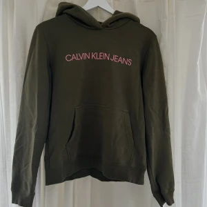 Calvin Klein hoodie  - Super snygg olivfärgad hoodie ifrån märket Calvin Klein. Tröjan har använts en del men är fortfarande i topp skick. Materialet är slitstarkt och trycket är precis som det ska. Inga slitage eller diffekter. Storlek S.