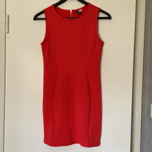 Klänning, korallfärgad - Klänning från divided i ett mycket fint skick, använd ett fåtal gånger.  Fin korallrosa färg och tight mot kroppen.   95% polyester, 5% elastan. 