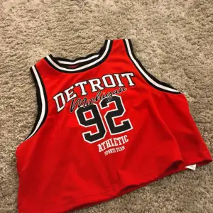 Red basketball top with black and white text 