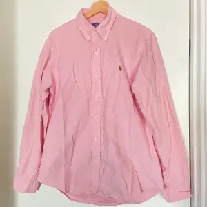 Rosa oxfordskjorta från Polo Ralph Lauren.  Det finns en lagning på baksidan längst ned vid skjortans slut, se bilder☺️ 