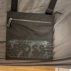 Boss (becknar väska)  - En Oanvänd man bag. köpte den i juli för 1100kr. Denär i bra skick inget som e sönder/trassigt (Pris kan diskuteras)   Höjd: 25 cm Längd: 24 cm Vidd: 2 cm