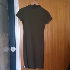 Grön klänning  - En militärgrön klänning som går ner lite under knäna. Köppt på bikbok i storlek S. Den är i bla skick. Polokrage.