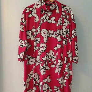 Blommig klänning från Zara - Cerisefärgad klänning med blommönster och tillhörande bälte. Aldrig använd 