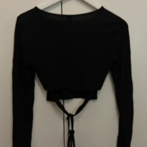 Svart tunn topp med knytning  - Bra skick, litet håll vid armen 
