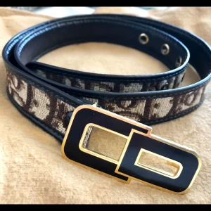 Dior Vintage skärp 75 cm - Brunt bälte från Dior med klassiskt monogram  Tyvärr va de för litet för mig  Super snyggt i midjan på blus och klänning  Skicket är jätte fint! Stämplar blivit slitna och pytte lite repor som knappt syns på spännet i övrigt UA 