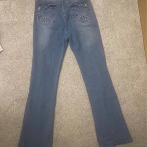 Jeans med dekoration fickor - Ett par blåa jeans med dekorerade fickor. Storlek xs. Som du ser p bilden så har en del gått av men d går att sy ihop den igen. 