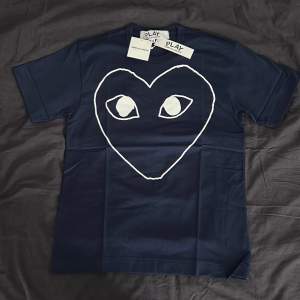 Mörkblå Comme des Garçons tshirt helt oanvänd. Nypris ligger på strax över 1000kr, säljes då den inte passar och blir dyrt med tullkostnader att skicka tillbaka. 