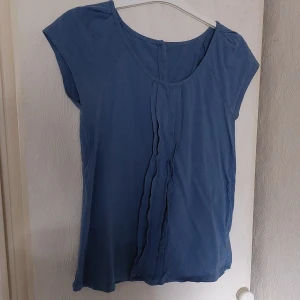 Blus med knappar bak - I bra skick. Bomull. Dekorvolanger fram och knappar bak. 