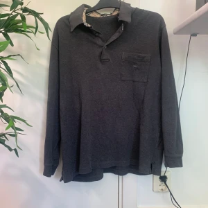 Burberrytröja - Burberrytröja med krage i bra skick. Har det klassiska burberrymönstret på insidan av kragen och burberryloggan på bröstfickan. Säljer då den är för stor för mig och knappt kommit till användning. Hör av er med frågor