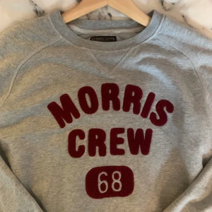 Morris - Lewis Sweatshirt - Grå Morris sweatshirt med rött bomulls-tryck, använd ett fåtal gånger men är som ny. Nypris: 1199kr Storlek: Herr - S