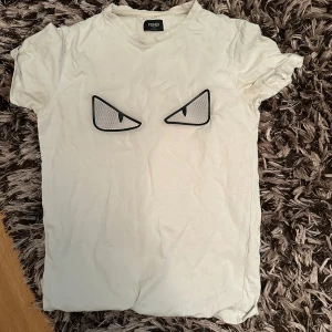Fendi T-Shirt - En Fendi T-shirt som säljs pga ej använd mer men den är topp topp skick och är en väldigt fin T-shirt förutom att en liten liten bit av det svarta runt det ena ögat sitter lite löst men därav det låga priset! Den är i storlek S! Den är såklart använd