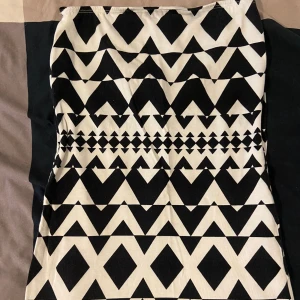 Svartvit kjol från Vero Moda - Säljer en superfin svartvit troja från Vero Moda i storlek XS. det har ett coolt geometriskt mönster med trianglar och andra former. Perfekt för både vardag och fest! 🖤🤍