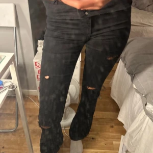 Svarta jeans med hål från Perfect Jeans - Säljer ett par svarta jeans från Perfect Jeans gina tricot i storlek XS. De är skinny/boutcut fit och har hål på knäna och låren för en cool, sliten look. De är i bra skick och har en hög midja men som är under naveln som sitter bekvämt men jag brukar vika ner dom och då blir dom lågmidjade annars kan man sy dom  till lågmidgat