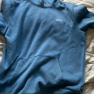Blå hoodie från Vans - Säljer en snygg blå hoodie från Vans. Den är superbekväm och perfekt för vardagsbruk. Hoodien har en stor ficka på magen och en liten Vans-logga på bröstet. Perfekt för höst och vinter! 💙