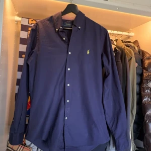  Ralph Lauren skjorta - Säljer en Ralph lauren skjorta i navy/mörkblå i väldigt bra skick med inga tecken på användning. Storlek S Bara att skriva vid frågor eller funderingar!