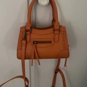 Orange väska  - Orange väska från Gina tricot finns inte kvar har använt några gånger men i nytt skick, de finns ett långt band me som man ser på sista bilden och kan även byta ut väska mot något🩷