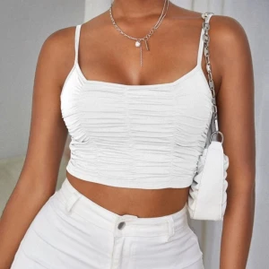 Vit croppad linnetopp - Säljer en snygg vit croppad linnetopp med smala axelband. Toppen har en rynkad design som ger en cool textur och är perfekt för sommaren. Den är tillverkad i ett mjukt och bekvämt material. Toppen är använd fåtal gånger!🤍