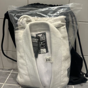 NY BJJ Kimono Bad Boy Legacy Master - Helt ny i originalförpackning! BJJ Kimono i märket Bad Boy.  Vit bomull. 550gsm Gold Weave bomull. Skall vara bekväm och slitstark. Innerfoder av mesh reglerar fukten så du håller dig torr. Förstärkt i områden som utsätts för mer stress med tredubbla
