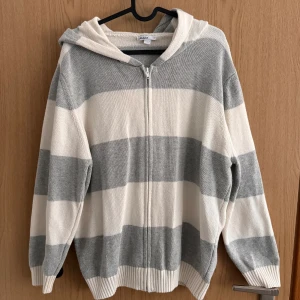 Randig stickad kofta  - En randig, stickad, tunn kofta i vitt och grått. Använd endast några enstaka gånger och är därmed i ett fint skick! 