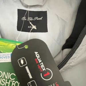 Reflex kappa ”skaljacka” - Reflex kappa med fast luva som kan stängas hela vägen. Lätt fodra med microfleece , vilket gör att den passar bra som skaljacka. Justerbar passform med dragsko i midjan  2st sidfickor med knappar Slits bak med knapp  Tvåvägs dragkedja fram. 