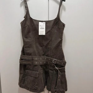 Klänning med detaljer zara - Jättesnygg klänning från zara. Helt slutsåld. Aldrig använd. Storlek 38 men passar 34/36/38. Grön/brun/grå färg med silverdetaljer