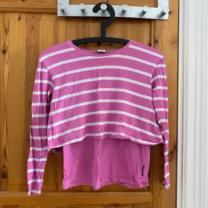 Randig rosa tröja som har används en del och normal i storleken. Det är som två lagar som ni ser på bilden. Rekommenderar från 8-10 år.