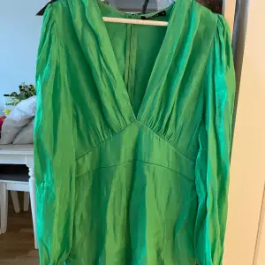 Fin klänning från Gina i skimrande grönt typ. Tunn och luftig med en dragkedja vid ryggen.   Finns ett litet hål i sömmen under dragkedjan (se bild 3).   Frakt tillkommer.