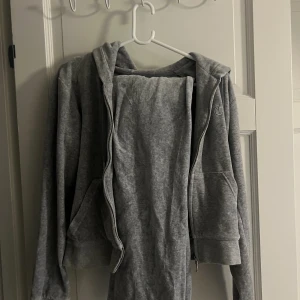 Juicy Couture set grå - Säljer ett ljusgrått Juicy Couture set i storlek M. Koftan är i fint skick, byxorna är lite mer slitna och har en svart fläck. Säljes för 400kr som set. Annars 450kr för koftan och 50kr för byxorna, med tanke på fläcken.