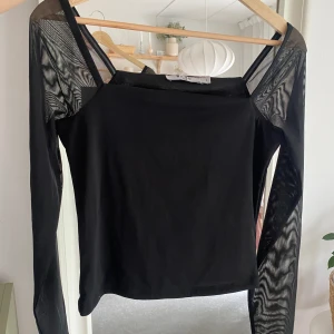 Svart topp - Svart topp från NA-KD med mesh på armarna! Storlek S