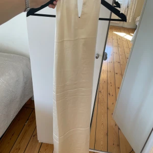 Beige siden klänning, öppen i ryggen  - En beige sidenklänning som är öppen i ryggen. Prislapp är kvar