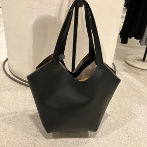 Zara väska - Svart läderväska köpt på ZARA i Spanien. Stor och rymlig, är använd några enstaka gånger. Har en liten fläck inuti och en pytteliten på utsidan som man verkligen inte tänker på om man inte kollar noga. 