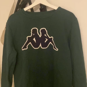 En kappa sweatshirt i bra skick - En mörkgrön sweatshirt från Kappa i storlek medium. Den är i bra skick och har mestadels legat i garderoben. Jag säljer denna eftersom jag har så mycket tjocktröjor och har redan en liknade till denna.