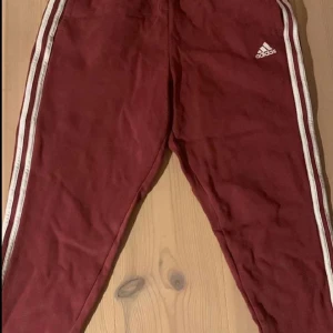 Adidas byxor mörk röda  - Äkta adidas byxor, Väger inte jättemycket och är i bra skick förutom att snörena på dom saknas, mjuka och sköna att ha på sig, är knappt använda 
