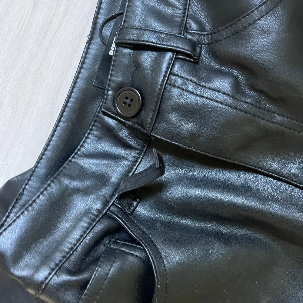 Säljer dessa svarta skinn/läder imitation byxor från bikbok. INTE äkta skinn. Svarta, storlek 34. Inte andvända så mycket men som bilden visar, där man sätter bältet, en av dessa är av.. Jeans & Byxor.