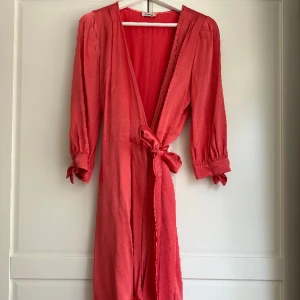 Klänning Valerie - Jätteskön och fin omlottklänning från Valerie i korallröd färg. Strl XS/S,  knytband i midjan. Nypris 2399kr. Använd 1 gång.