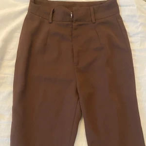 Bruna kostymbyxor - Ett par bruna kostymbyxor från vero moda, lappen är ej kvar men passar mig som har xs och byxorna är höga i midjan 