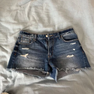 JEANSSHORTS - mörkblå jeansshorts med slitningar. Låga/medel i midjan. Väldigt bra skick! Skriv för fler bilder💙