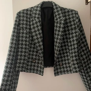 Svart och mörkgrönt rutig kavaj - Säljer denna eleganta mörk grön och vit rutiga kavaj med långärmad design. Kavajen har en croppad passform och är försedd med knappar framtill. Aldrig använd! 🤍✨🌸