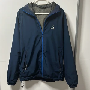 Blå vindjacka från Haglöfs - Haglöfs GTX Chaos Jacka. Köpt för 3600kr. Storlek S men lite större i storlek. Jackan har en huva och är fodrad med nätmaterial för extra ventilation. Använd ett par gånger, men är i nytt skick.