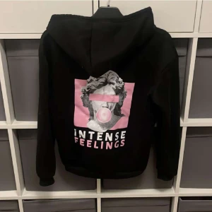 Svart hoodie - "INTENS FEELINGS" hoodie, tryck på baksidan. Säljer för 40kr. Pris kan diskuteras vid snabb affär. Säljer då den inte kommer till användning. Skicket är som nytt. Material som en helt vanlig hoodie, ludd inuti. Storlek XS-S😊
