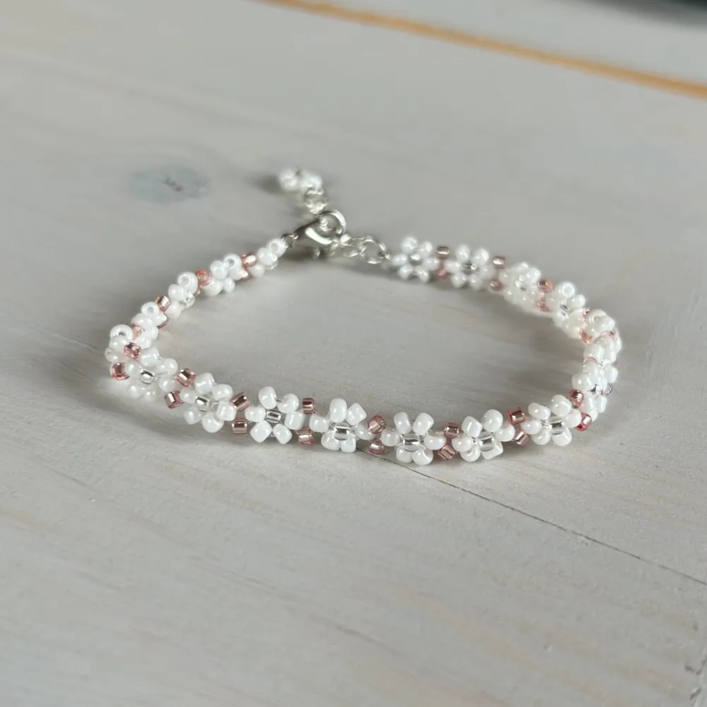 Handgjort armband med vita blommor och detaljer i rosé. . Accessoarer.