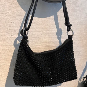 Glitter väska  - Svart glitterväska i nytt skick då den är använd endast en gång. Väldigt rymlig och justerbar 