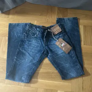 Mörkblå/gråa jeans i spräcklig färg. Flare. Mått: midja rakt över 35cm. Innerbenslängd 78 cm. w26 l32