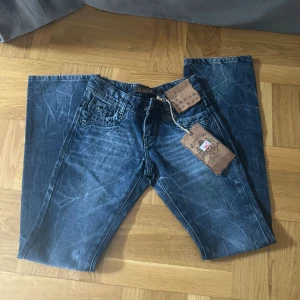 Vintage jeans - Mörkblå/gråa jeans i spräcklig färg. Flare. Mått: midja rakt över 35cm. Innerbenslängd 78 cm. w26 l32