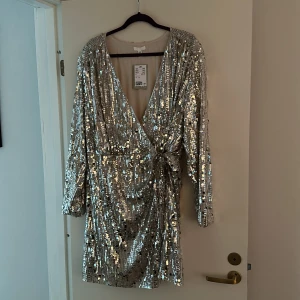 Paljettklänning  - Oanvänd paljettklänning, omlott fram med knytning. Nypris 549
