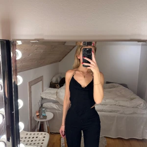 Svart top  - Svart top med ringar i metall och snörning baktill. 