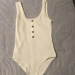 Vit body - 1 st vit body med knappar. Använd endast en gång och inga tecken på användning. Säljer pga att den aldrig används. Priset kan diskuteras.